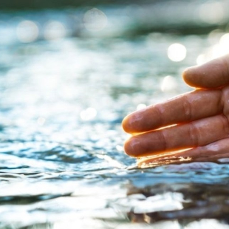 Right hand in river with water flowing